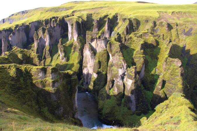 Chute d'eau jaillissant des rochers verts de mousse, en Islande