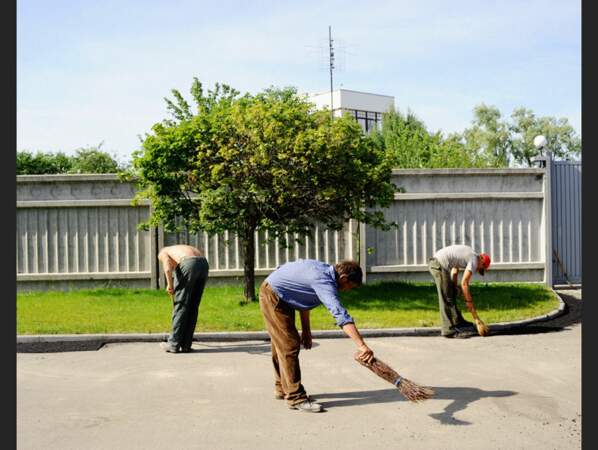 Des employés balaient devant les datchas de milliardaires, à Strakholessie, non loin de la zone contaminée de Tchernobyl, en Ukraine.