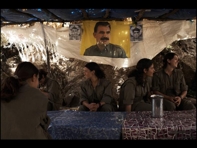 Au camp de l'Yja Star, la section féminine de l'Armée de libération du peuple (HPG) se retrouve au réfectoire. Derrière ces femmes, se trouvent les portraits du Président du PKK, Abdullah Ocalan ainsi que des photos de deux jeunes martyrs de la lutte de libération.