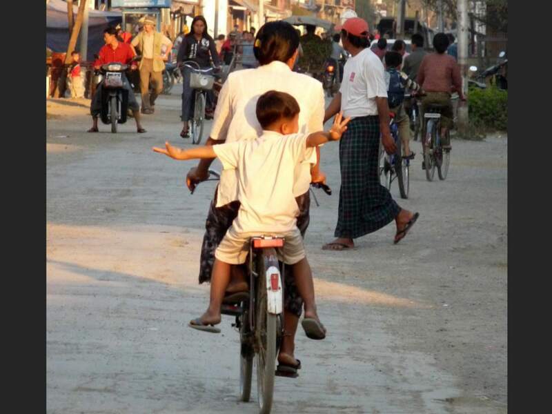 Un enfant, sur la bicyclette de sa mère, en Birmanie.