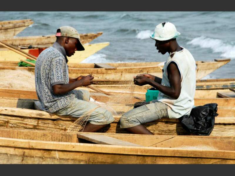 Deux hommes réparent un filet de pêche au bord du lac Tanganyika, au Burundi, en Afrique.