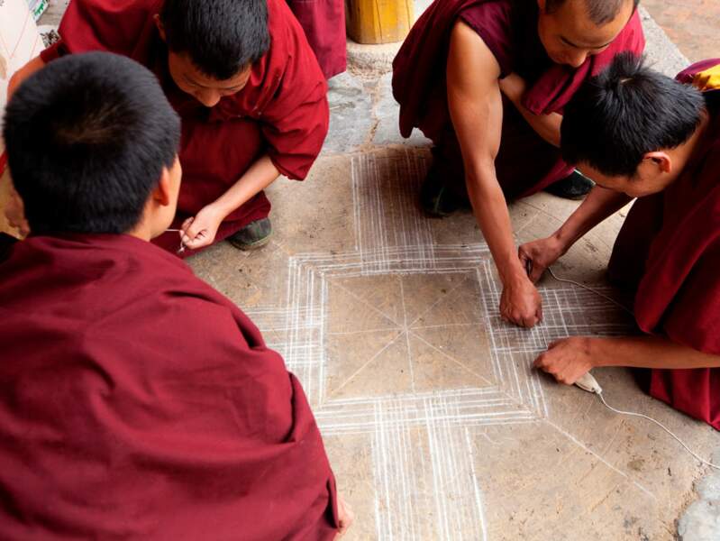 De jeunes moines dessinent un mandala, une figure bouddhique. 