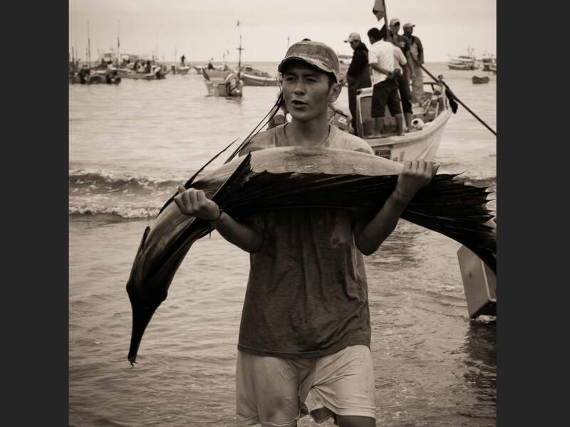 Un jeune pêcheur fier de sa prise sur la plage de Puerto López, en Equateur.