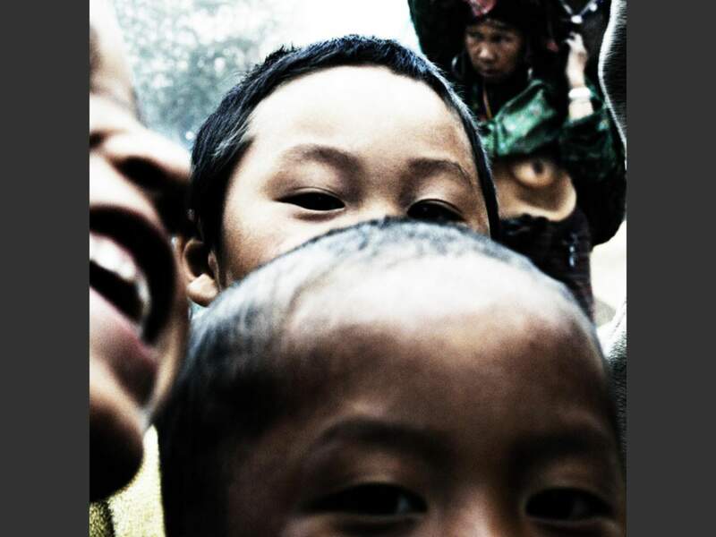 Un groupe d’enfants est attiré par l’appareil, dans un village du Laos.