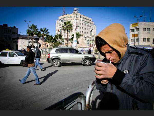 Un homme allume une cigarette dans une rue de Ramallah, en Palestine (Cisjordanie).