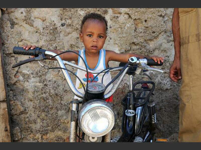 Un jeune enfant s'imagine en motard au marché de Mindelo, au Cap-Vert.