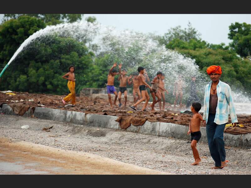Près de Bassi, au Rajasthan (Inde), ces enfants profitent du jet d'eau des cantonniers pour se rafraîchir. 