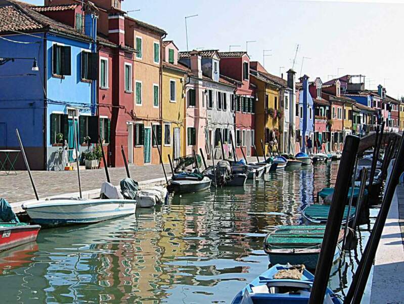 Les couleurs des façades se reflètent dans l'eau des canaux, sur l'île de Burano, dans la lagune de Venise (Italie).