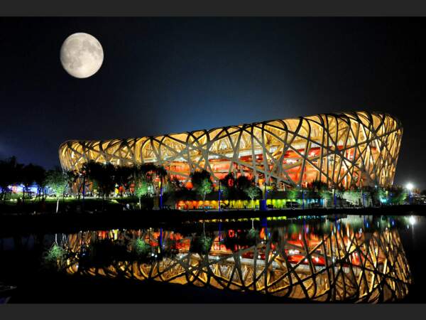 La lune éclaire le ciel au-dessus de " nid d'oiseau ", le stade olympique chinois.