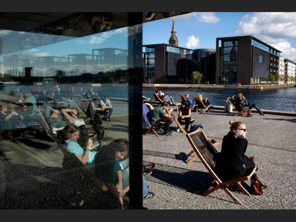 Les gens profitent du soleil sur la terrasse devant le « diamant noir », à Copenhague (Danemark).