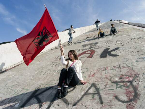 Une jeune fille porte un drapeau albanais au palais de la culture, à Tirana, en Albanie