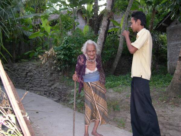 Mas Oka salue Mbah Udi, sa vieille voisine, sur un chemin de Bebekan (Java, Indonésie).