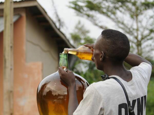 Un vendeur de kpayo transvase de l’essence d’une bouteille à une bonbonne.