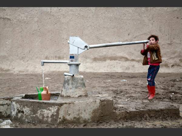 Un enfant puise de l'eau à l'aide d'une pompe à mains, en Afghanistan.
