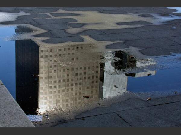 Des bâtiments se reflètent dans une flaque à La Défense, dans les Hauts-de-Seine, en France.