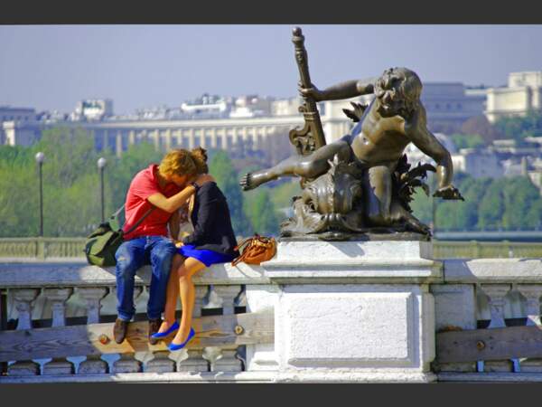 Deux amoureux s'embrassent sur le pont Alexandre III, à Paris.