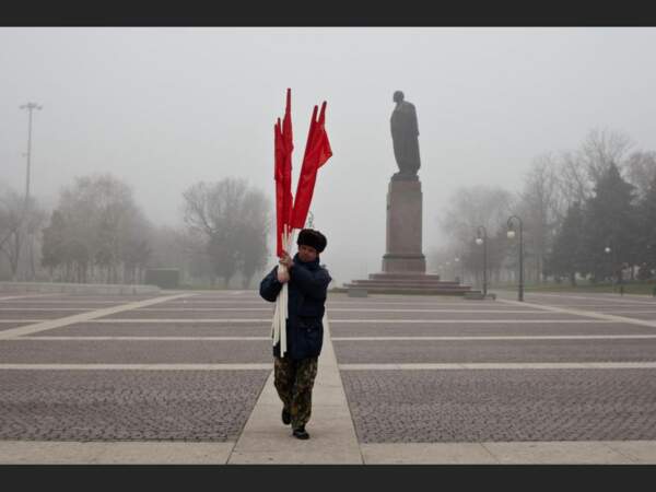 Un homme porte des drapeaux devant la statue de Lénine près du Kremlin d'Astrakhan, en Russie.