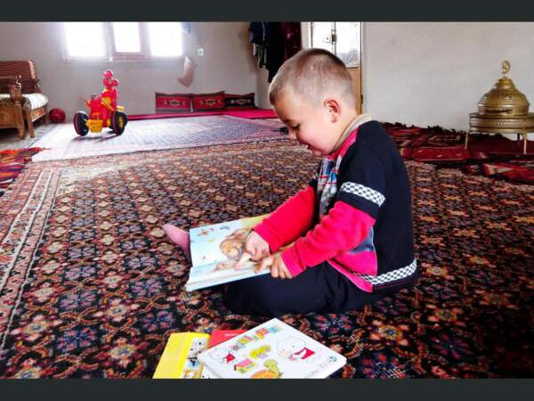 Un jeune enfant s’amuse avec des livres à Alep, en Syrie.