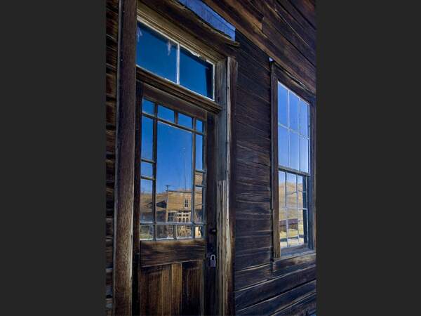 Les mines abandonnées de Bodie se reflètent dans les vitres d’une vieille bâtisse (Californie, Etats-Unis).