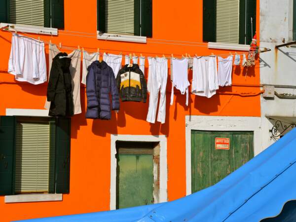 Des vêtements prennent le soleil le long d'une maison de Burano, dans la lagune de Venise, en Italie