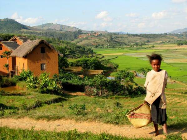 Cette petite fille se tient devant un paysage typique du Betsileo, dans les hauts plateaux de Madagascar.