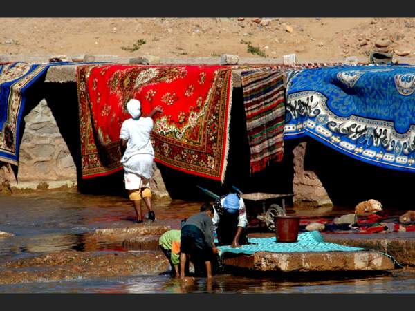 Des femmes et des enfants lavent des tapis dans une oued de la région d’Aït-Benhaddou, au Maroc