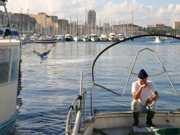 Un pêcheur se distrait après une matinée de travail, dans le Vieux Port de Marseille, en Provence-Alpes-Côtes d’Azur, en France