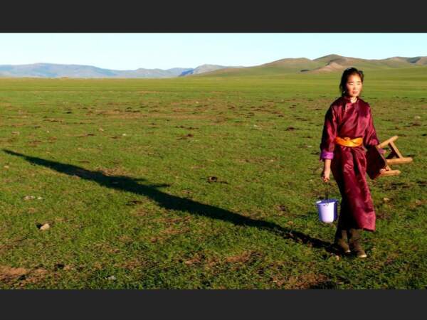 Jeune femme au petit matin, transportant ses outils de traite (Mongolie).