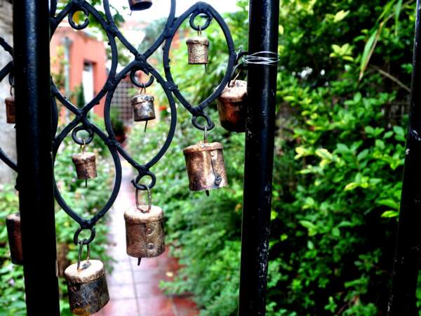 Un petit portail en fer forgé agrémenté de clochettes dans un jardin privé de Belleville, à Paris (France).